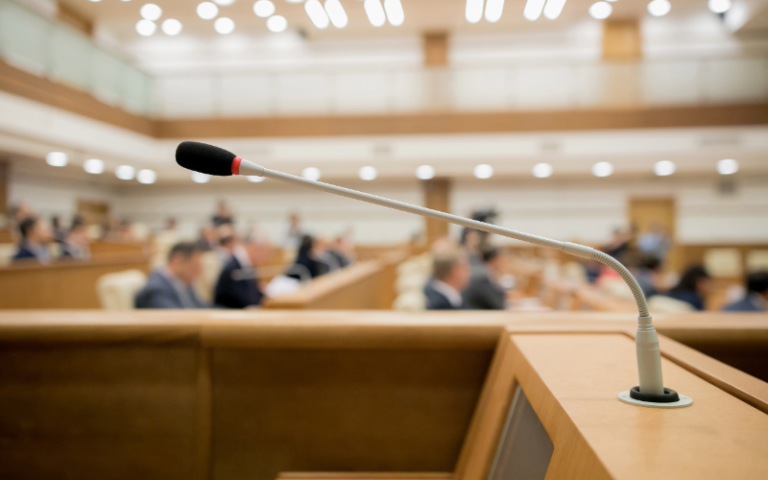 A close-up of a microphone at a lectern in city council chambers.